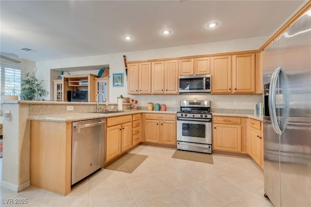 kitchen with appliances with stainless steel finishes, light brown cabinetry, sink, kitchen peninsula, and light stone countertops