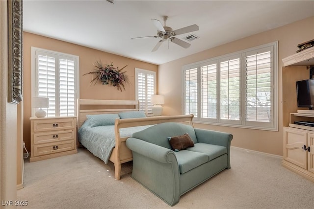 bedroom with ceiling fan, light carpet, and multiple windows