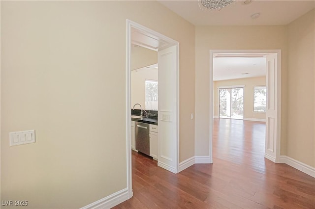 hallway with a sink, baseboards, and wood finished floors