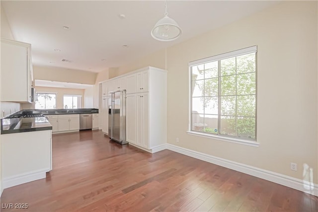 kitchen with white cabinetry, appliances with stainless steel finishes, sink, and decorative light fixtures