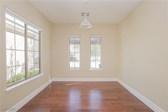 unfurnished room featuring baseboards, dark wood-type flooring, and visible vents