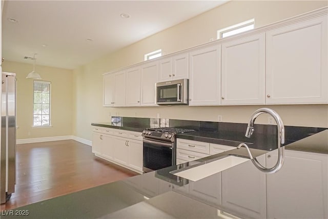 kitchen with baseboards, dark wood finished floors, appliances with stainless steel finishes, and white cabinets