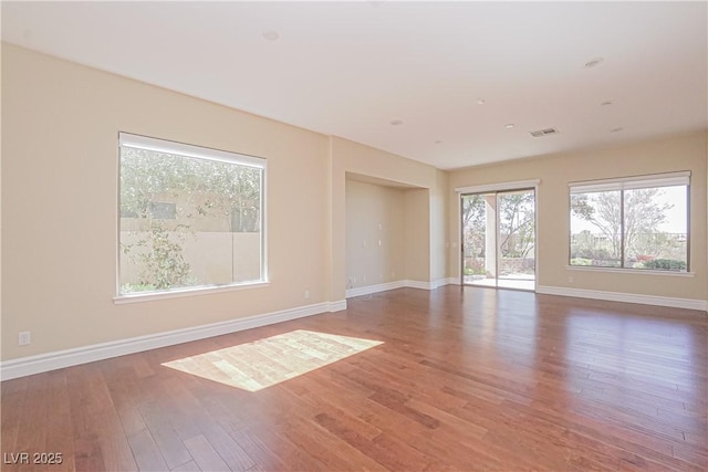 spare room with visible vents, baseboards, and wood finished floors