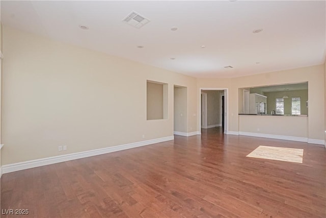 empty room with visible vents, baseboards, and wood finished floors