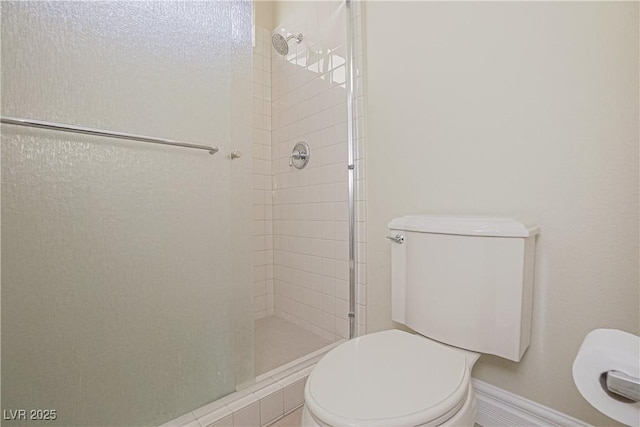 bathroom with toilet, baseboards, and a shower stall