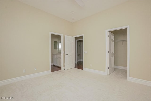 unfurnished bedroom with connected bathroom, a walk in closet, a closet, and carpet