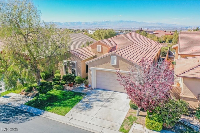 view of front of house with a garage, a mountain view, and a front lawn