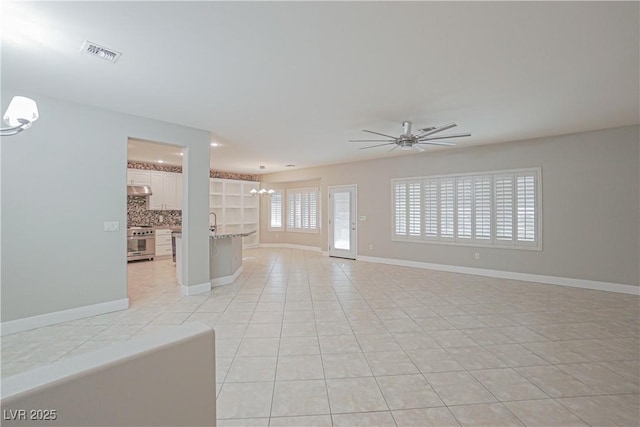 unfurnished living room featuring ceiling fan with notable chandelier, sink, and light tile patterned floors