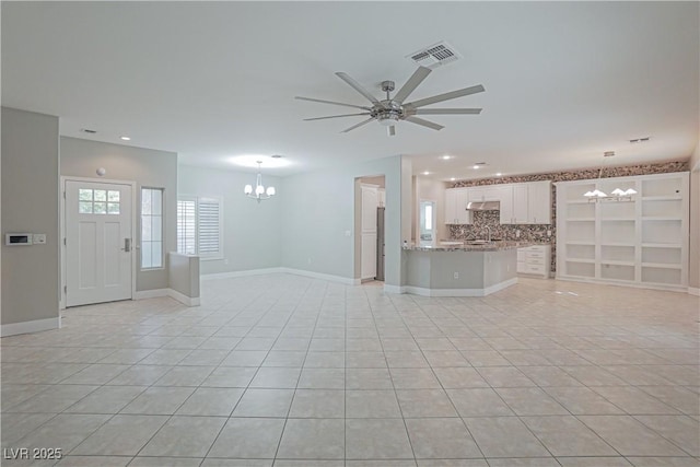 unfurnished living room featuring light tile patterned flooring and ceiling fan with notable chandelier