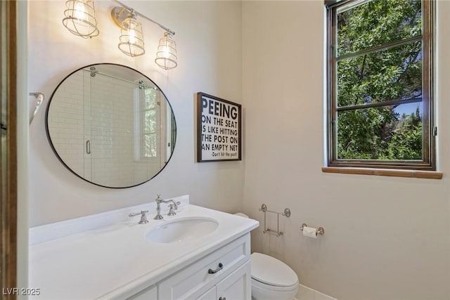 bathroom with vanity, toilet, a wealth of natural light, and walk in shower