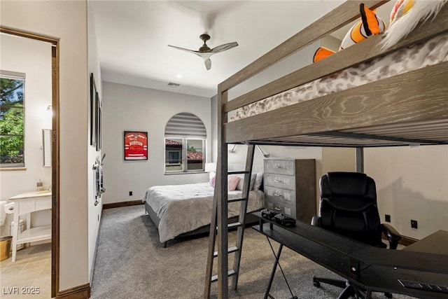 bedroom featuring ceiling fan, connected bathroom, and light carpet