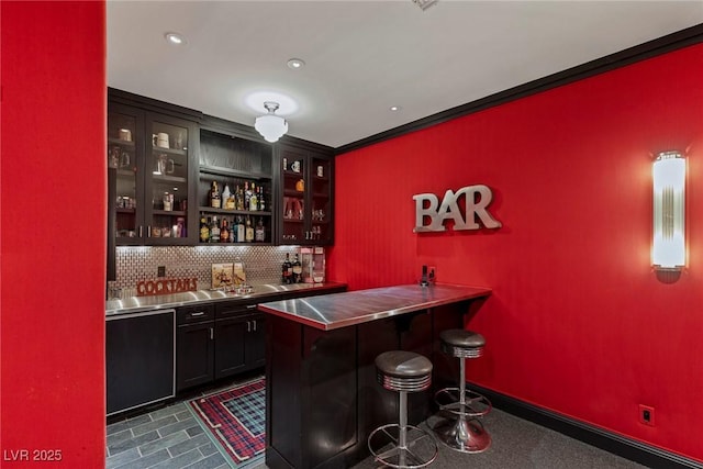 bar with crown molding, dishwasher, stainless steel counters, and backsplash