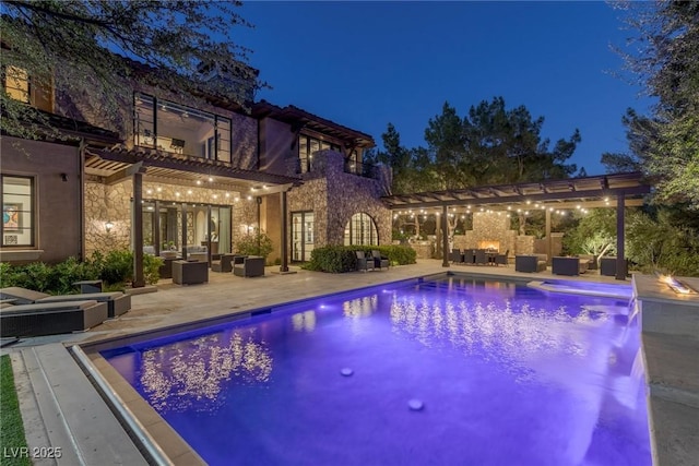 pool at twilight featuring a pergola, a patio, an outdoor living space with a fireplace, and exterior kitchen