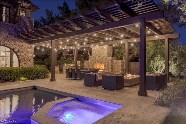 pool at night featuring area for grilling, an outdoor living space with a fire pit, an in ground hot tub, a pergola, and a patio area