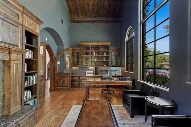 office featuring hardwood / wood-style flooring, beamed ceiling, and a towering ceiling