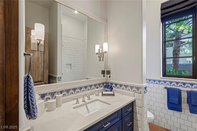 bathroom with tile walls, vanity, a tile shower, tile patterned floors, and toilet