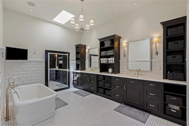 bathroom featuring a washtub, vanity, decorative backsplash, and an inviting chandelier