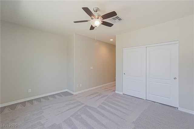 unfurnished bedroom featuring light carpet, ceiling fan, and a closet