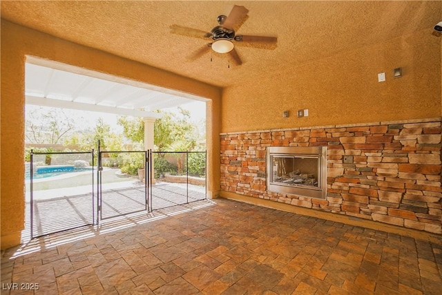 interior space with ceiling fan and an outdoor stone fireplace