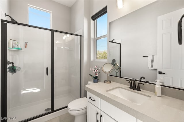 bathroom with a shower with door, vanity, a wealth of natural light, and toilet