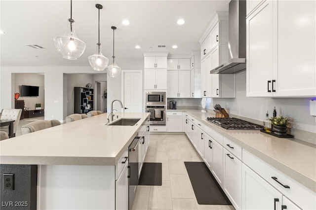 kitchen featuring a spacious island, wall chimney exhaust hood, stainless steel appliances, and sink