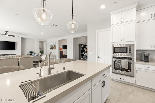 kitchen featuring pendant lighting, sink, light tile patterned floors, stainless steel appliances, and white cabinets