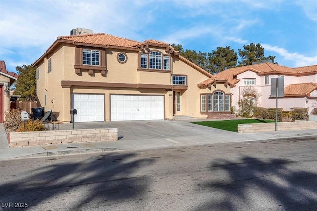 mediterranean / spanish house with a tile roof, stucco siding, fence, a garage, and driveway