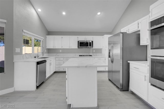 kitchen with stainless steel appliances, a center island, vaulted ceiling, and a sink