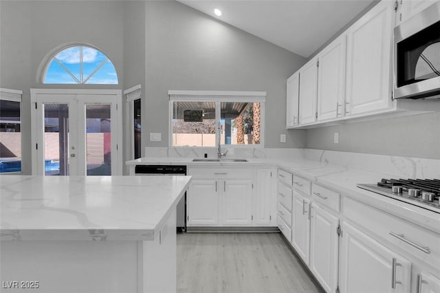 kitchen with stainless steel appliances, a sink, light stone countertops, and white cabinets