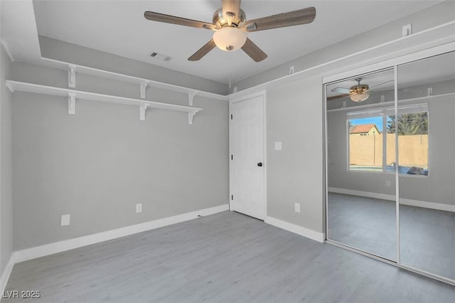 unfurnished bedroom featuring a ceiling fan, visible vents, baseboards, and wood finished floors