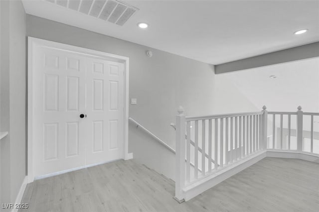 corridor featuring baseboards, visible vents, wood finished floors, an upstairs landing, and recessed lighting