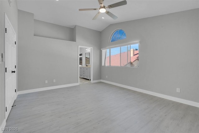 unfurnished bedroom featuring ensuite bathroom, vaulted ceiling, baseboards, and wood finished floors