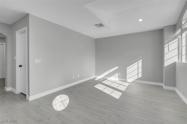 empty room with baseboards, visible vents, arched walkways, and wood finished floors