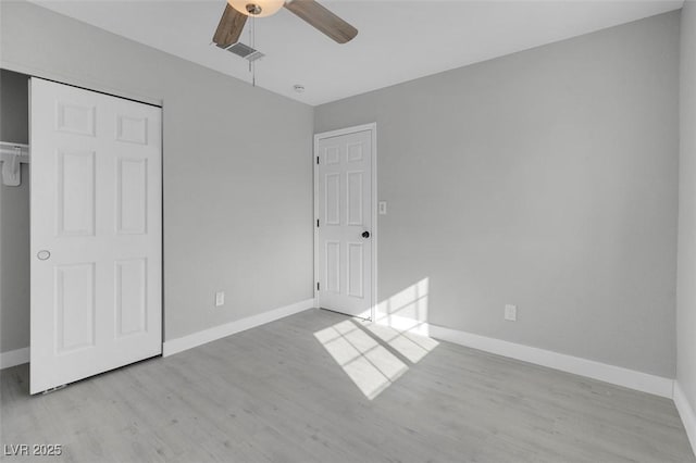 unfurnished bedroom featuring visible vents, a closet, baseboards, and wood finished floors