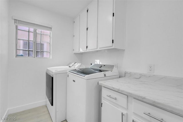 laundry room featuring light wood-style floors, washer and clothes dryer, cabinet space, and baseboards