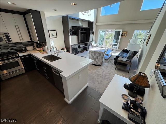 kitchen with appliances with stainless steel finishes, white cabinetry, sink, dark carpet, and kitchen peninsula