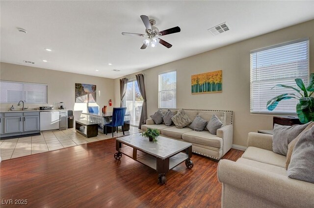 living room featuring a healthy amount of sunlight, sink, and light hardwood / wood-style floors