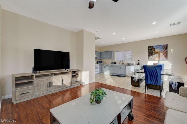 living room featuring sink, ceiling fan, and light hardwood / wood-style flooring