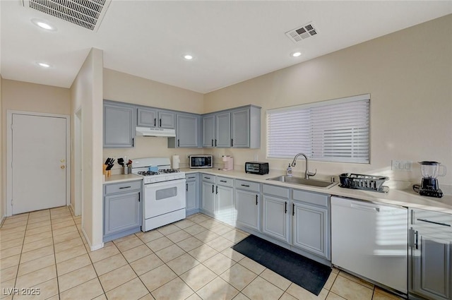 kitchen featuring sink, white appliances, gray cabinets, and light tile patterned floors