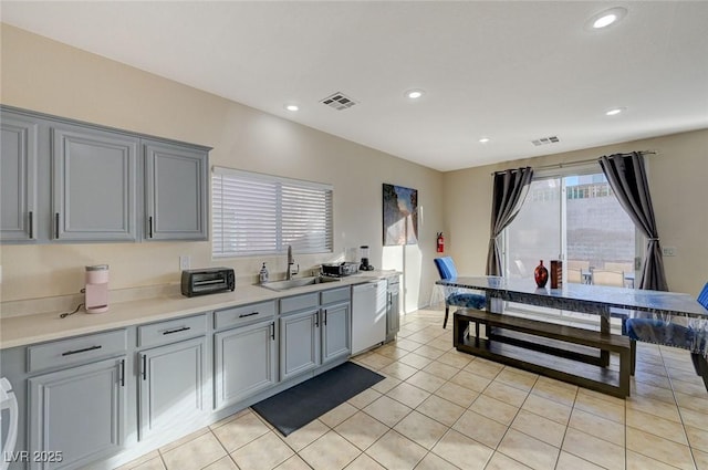 kitchen featuring dishwasher, sink, light tile patterned floors, and gray cabinetry