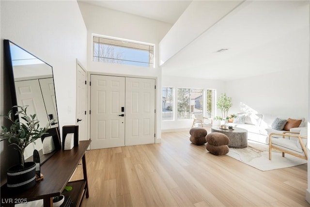 entryway featuring a towering ceiling and light hardwood / wood-style floors