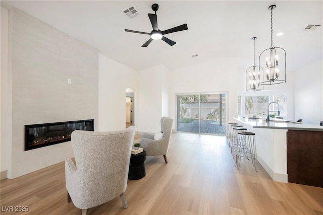 living room with sink, a fireplace, light hardwood / wood-style floors, and ceiling fan