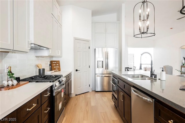 kitchen with sink, appliances with stainless steel finishes, white cabinetry, hanging light fixtures, and dark brown cabinetry