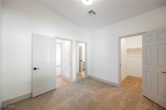 unfurnished bedroom with light colored carpet, lofted ceiling, a spacious closet, and a closet