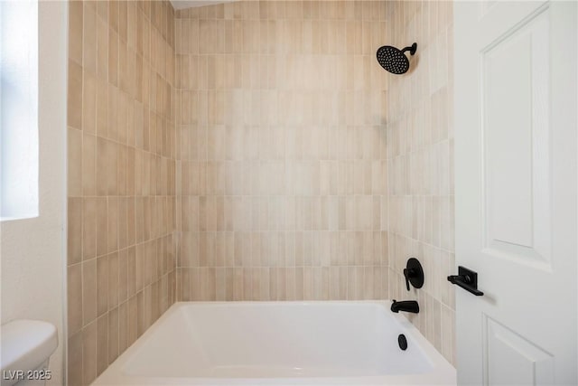 bathroom featuring tiled shower / bath and toilet