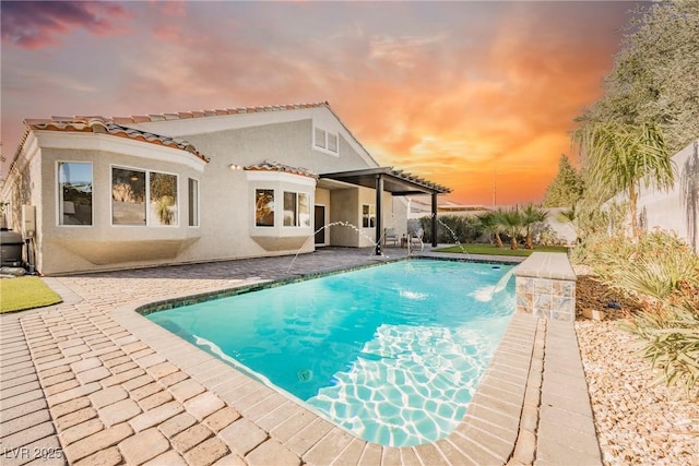 back house at dusk featuring a patio area