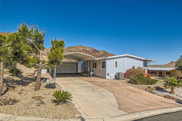 view of front facade with driveway, central AC unit, a mountain view, and a detached carport