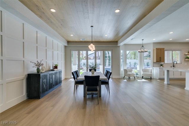 dining room with wood ceiling, a chandelier, sink, and light hardwood / wood-style flooring