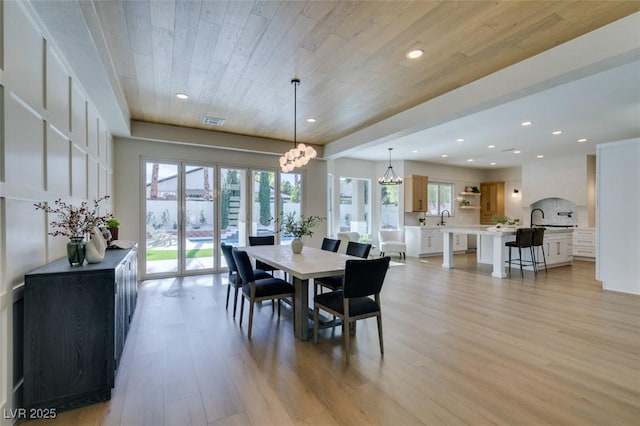 dining space with sink, wooden ceiling, light hardwood / wood-style floors, and a chandelier