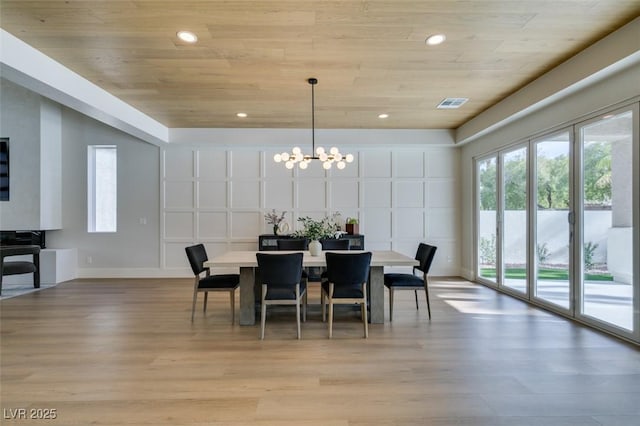 dining space with light wood-type flooring, an inviting chandelier, and wood ceiling